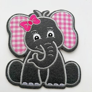May include: A gray elephant applique with a pink bow and pink and white gingham ears. The elephant has a gray outline and is sitting down. The applique is made of felt and is suitable for sewing or crafting projects.