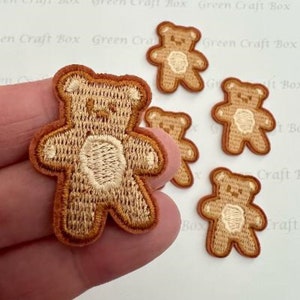 May include: Five brown embroidered iron-on patches of teddy bears. The bears are outlined in a darker brown and have a beige face.