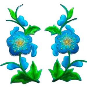 May include: Two blue embroidered flower patches with green leaves and stems. The flowers have a yellow centre with a blue and white swirl.