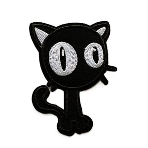 May include: A black embroidered patch in the shape of a cartoon cat with a large round head, wide white oval eyes, pointed ears with white inner details, a thin body, and a curved tail. The design features thick black stitching throughout.