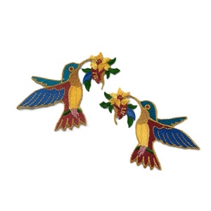 May include: Two embroidered iron-on patches of hummingbirds with blue wings, yellow bodies, and red beaks, each with a yellow flower in their beaks.