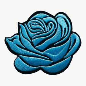 May include: An embroidered patch in the shape of a blooming rose. The flower features vibrant light blue thread for the petals, creating a textured appearance, and is outlined with a thick, solid black border that defines its organic shape.