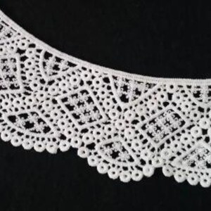 May include: White lace trim with a delicate, intricate pattern. The lace has a scalloped edge and is perfect for adding a touch of elegance to any project.