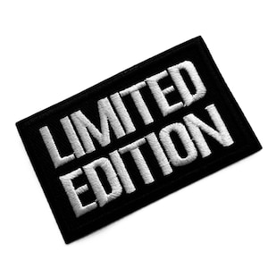 May include: A rectangular embroidered patch with a black background and the words LIMITED EDITION stitched in bold white capital letters. The patch features a clean, stitched border and a high-contrast design with a textured thread finish.