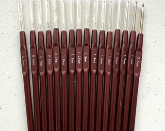 May include: A set of 16 burgundy crochet hooks with clear plastic handles. The hooks are arranged in order of size, from 0.5 mm to 2.5 mm. Each hook is labeled with its size in millimeters.