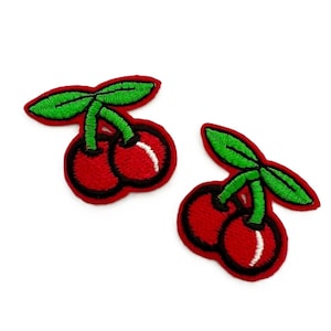 May include: Two red embroidered cherries with green stems and leaves. The cherries are stitched with a white highlight.