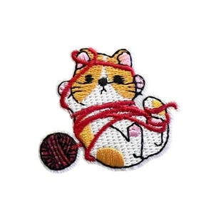 May include: Embroidered iron-on patch of a white and orange cat tangled in red yarn with a ball of yarn in the background.