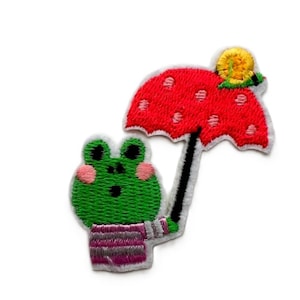 Könnte beinhalten: Ein grüner Frosch mit einem gestreiften Hemd hält einen roten und weißen gepunkteten Regenschirm mit einer gelben Schnecke oben drauf.