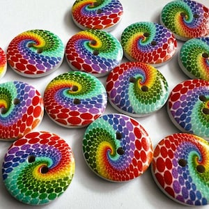 May include: A collection of round, two-hole buttons featuring a vibrant, multi-coloured spiral pattern. Each button displays a gradient of red, orange, yellow, green, blue, and purple dots arranged in a swirling design on a white background.