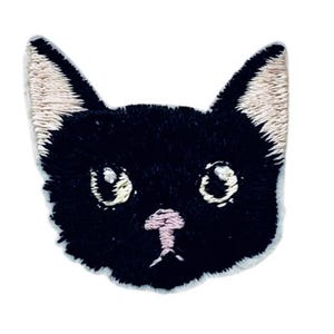 Peut inclure: Patch brodé noir en forme de tête de chat avec des oreilles blanches et un nez rose.