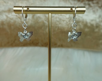 May include: A pair of silver butterfly earrings with clear rhinestone accents. The earrings are hanging from a gold stand.