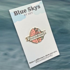 May include: A pin featuring a stylized brain design with the words "Mental Health Matters" on a banner. The pin is set against a white card with the text "Blue Skys by Sky" and a call to action: "Make a difference, show you care."