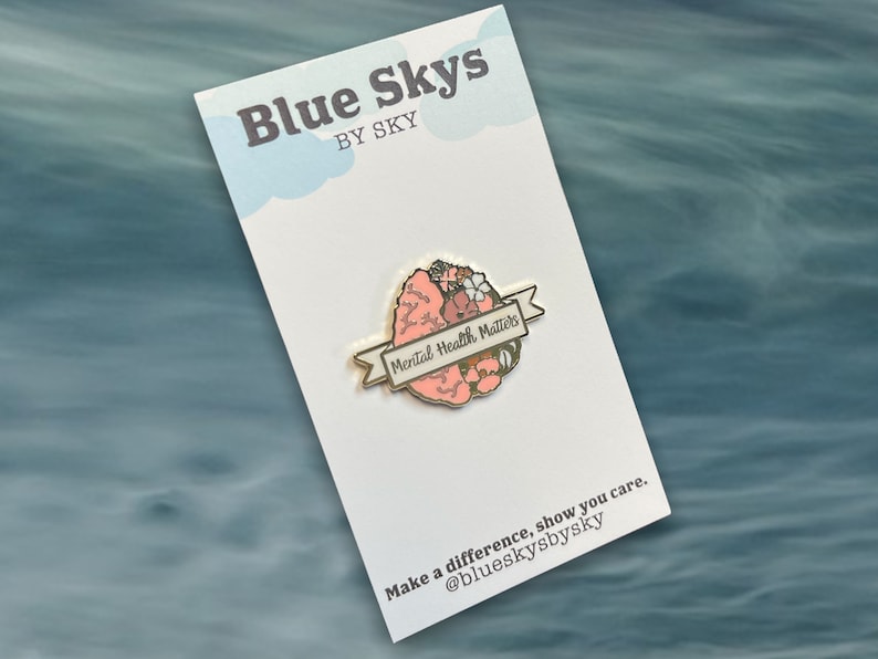 May include: A pin featuring a stylized brain design with the words "Mental Health Matters" on a banner. The pin is set against a white card with the text "Blue Skys by Sky" and a call to action: "Make a difference, show you care."