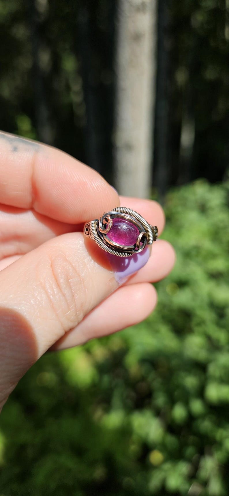 May include: A silver and copper wire wrapped ring with a pink oval gemstone.