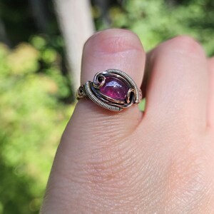 May include: A ring with a purple gemstone set in a silver and copper wire design.