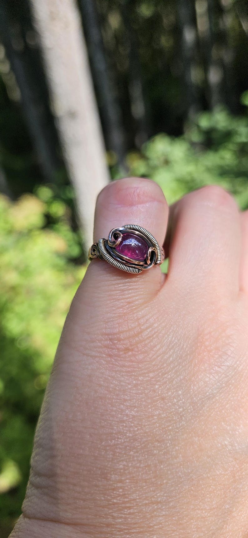 May include: A ring with a purple gemstone set in a silver and copper wire design.