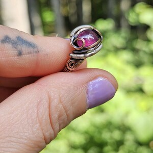 May include: A ring with a pink gemstone set in a silver and copper wire wrapped setting.