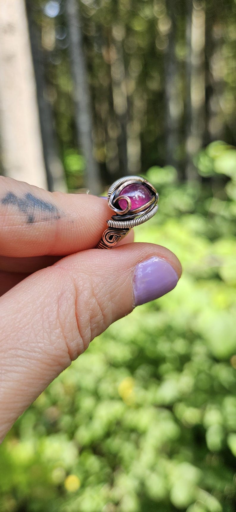 May include: A ring with a pink gemstone set in a silver and copper wire wrapped setting.