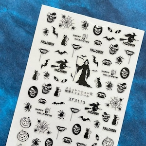 May include: A sheet of Halloween-themed nail art stickers. The stickers feature black and white images of pumpkins, spiders, bats, cats, skulls, witch silhouettes, and the text "HALLOWEEN" and "HAPPY HALLOWEEN". The product code is XF3113.