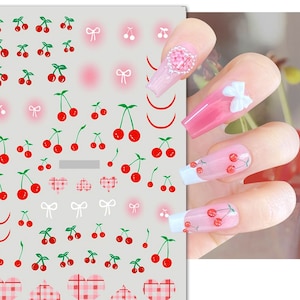 May include: A sheet of nail stickers with a variety of cherry designs, including cherries with stems and leaves, cherries with bows, and cherries with hearts. The stickers are on a white background.