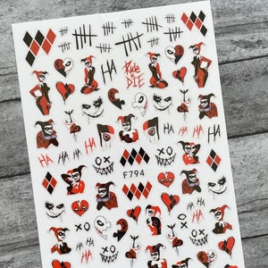 May include: A sheet of nail art stickers featuring a red and black Harley Quinn design. The stickers include images of Harley Quinn, hearts, diamonds, and the text "Ride or Die".