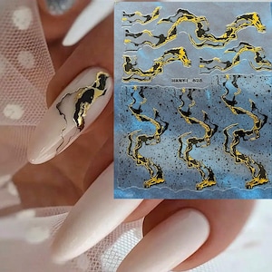 May include: Nail art stickers with a gold and black marble design. The stickers are on a blue background with a marble pattern. One nail is painted with the marble design. The stickers are labelled HANYI-626.