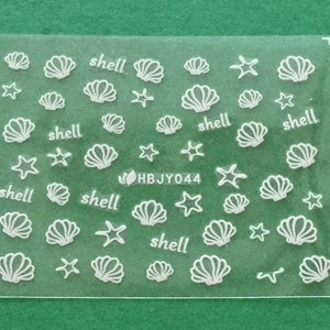 May include: A sheet of white nail decals with images of seashells and starfish. The sheet has the text "shell" printed five times and the code "HBJY044" printed once.