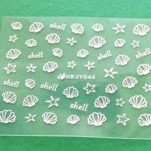 May include: A sheet of white nail decals with images of seashells and starfish. The sheet has the text "shell" repeated multiple times.