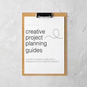 Op de afbeelding: Een wit clipboard met een bruin frame, met een document met de tekst "creative project planning guides" en de tekst "a series of guides to help plan + strategize in your creative projects //".