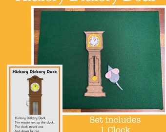 May include: A felt play set for the nursery rhyme "Hickory Dickory Dock". The set includes a brown grandfather clock with a white mouse. The clock has a white face with black numbers and hands. The mouse is white with pink ears and a long tail. The set is on a green felt background.