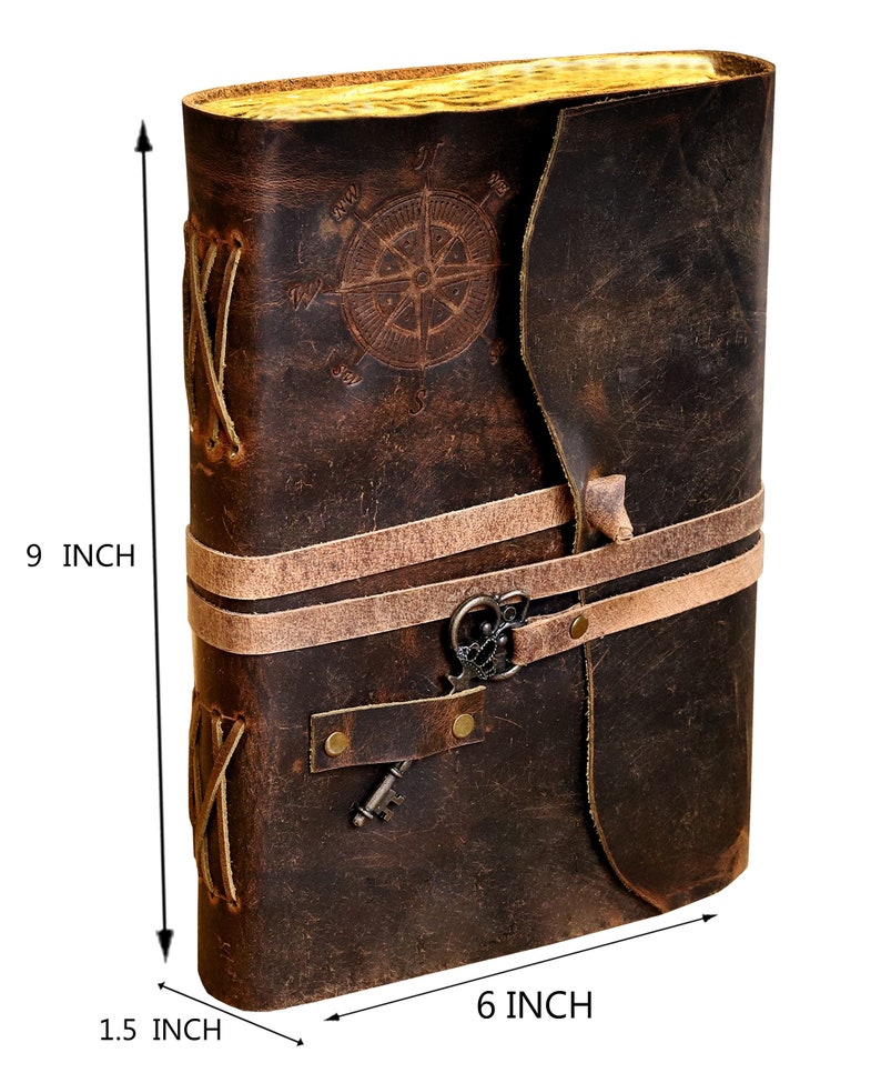 May include: A brown leather journal with a compass design on the front cover. The journal has a key and a leather strap closure. It measures 9 inches tall and 6 inches wide.