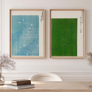Puede incluir: Dos láminas rectangulares enmarcadas con diseños de estilo xilografía japonesa. La lámina izquierda muestra un paisaje azul con aves blancas, la derecha un campo verde sólido con aves oscuras, ambas con texto japonés vertical.