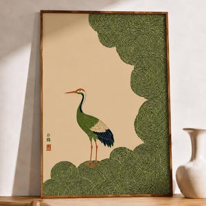 Peut inclure: Une impression d'art murale encadrée rectangulaire représentant une grue debout sur des nuages verts tourbillonnants stylisés sur un fond beige clair. La grue a un corps vert, des plumes d'ailes blanches et noires et une crête rouge.