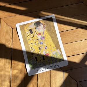 Pu&ograve; includere: Un poster del dipinto "Il Bacio" di Gustav Klimt. Il dipinto presenta due figure in un abbraccio dorato, circondate da motivi intricati e floreali.