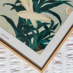 May include: A framed print of a Japanese woodblock print featuring white lilies and green leaves. The print is titled "Koson" in the bottom left corner.