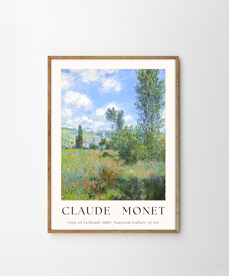 Op de afbeelding: Een ingelijste print van een schilderij van Claude Monet getiteld "Uitzicht op V&eacute;theuil, 1880". Het schilderij toont een landschap met een dorp in de verte, een veld met rode klaprozen en een hoge boom op de voorgrond.