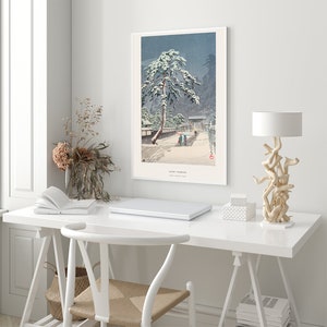 May include: A snowy landscape with a pine tree covered in snow and a small group of people walking on a path. The image is a Japanese woodblock print titled "Yuki-Fumi" by Kawase Hasui.