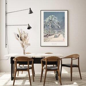 May include: A dining room with a white marble table and four wooden chairs. A black wall-mounted light fixture with two shades is on the left side of the image. A framed print of a snowy Japanese landscape hangs on the wall behind the table. The print features a pine tree covered in snow and the text "Yuki-Yama" in the bottom right corner.