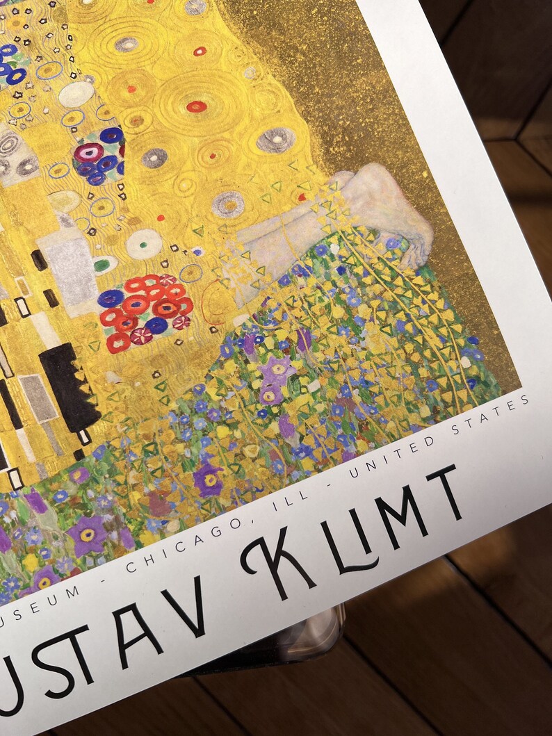 Pu&ograve; includere: Un primo piano di un poster per l'Art Institute di Chicago che presenta un dipinto di Gustav Klimt. Il dipinto &egrave; un ritratto di una donna con uno sfondo dorato e un motivo floreale nella parte inferiore. Il testo "MUSEUM - CHICAGO, ILL - UNITED STATES" e "GUSTAV KLIMT" sono visibili nella parte inferiore del poster.
