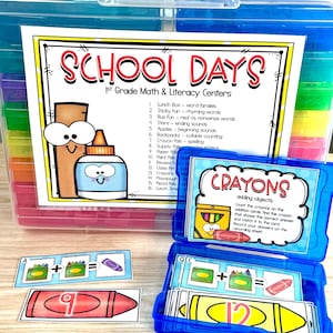 May include: A clear plastic storage container filled with colorful school supplies. The container holds educational materials for 1st grade math and literacy, including flashcards and a box labeled "Crayons". The text "School Days" is visible.