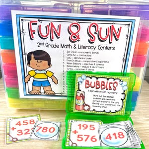 May include: A colorful educational set labeled "FUN & SUN" for 2nd grade math and literacy. Includes cards with addition problems and answers, plus a "BUBBLES" card. The set is stored in clear plastic containers with various colored lids.
