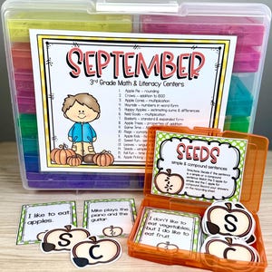 May include: A clear plastic storage container filled with educational materials for 3rd grade math and literacy. The container includes cards, apple-shaped cutouts, and a label that reads "September". The image also shows the text "Seeds simple & compound sentences".