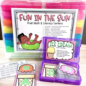 May include: A clear plastic storage container with a pink lid, filled with colorful compartments. The container holds educational materials for PreK math and literacy, including letter matching cards with ice cream cone illustrations. The text "FUN IN THE SUN" is visible.