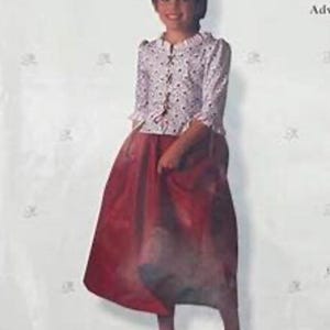 May include: A young person wearing a colonial school outfit. The outfit includes a white blouse with a floral pattern and a long, red skirt. The person is wearing black shoes. The image is set against a white background.