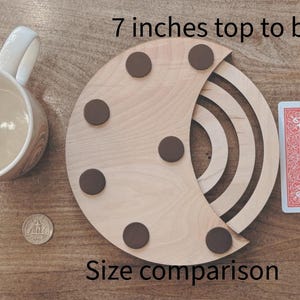 May include: A wooden crescent-shaped coaster with six brown circular pads, measuring 7 inches from top to bottom. A playing card, a pencil, a mug, and a coin are included for size comparison. The text "Size comparison" is also visible.