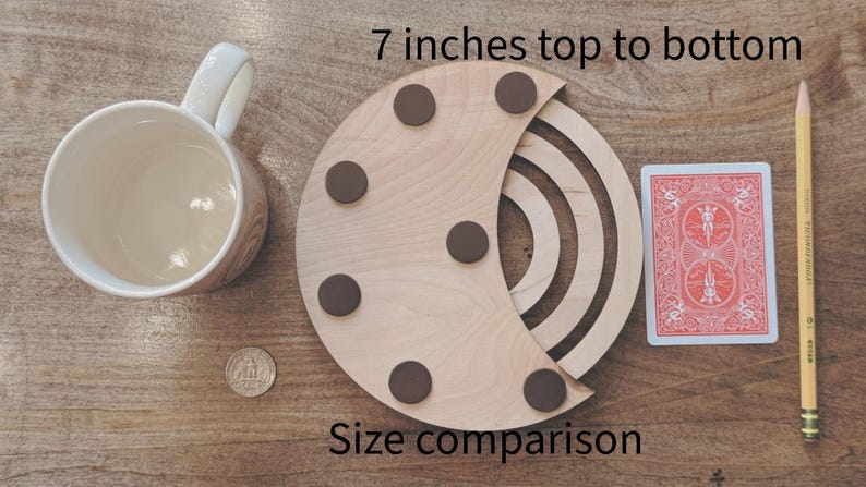 May include: A wooden crescent-shaped coaster with six brown circular pads, measuring 7 inches from top to bottom. A playing card, a pencil, a mug, and a coin are included for size comparison. The text "Size comparison" is also visible.