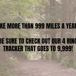 May include: Image with text: "HIKE MORE THAN 999 MILES A YEAR? BE SURE TO CHECK OUT OUR 4 RING TRACKER THAT GOES TO 9,999!" The background is a forest trail with trees on either side.
