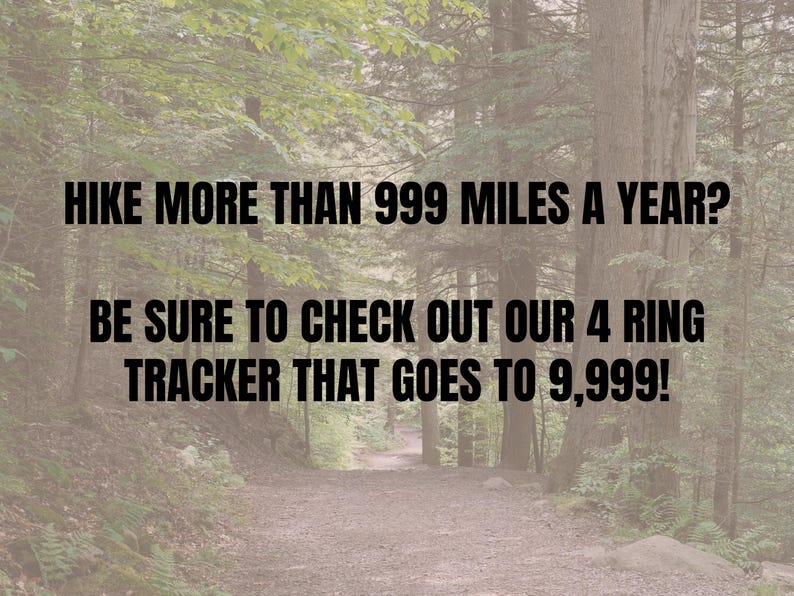 May include: Image with text: "HIKE MORE THAN 999 MILES A YEAR? BE SURE TO CHECK OUT OUR 4 RING TRACKER THAT GOES TO 9,999!" The background is a forest trail with trees on either side.