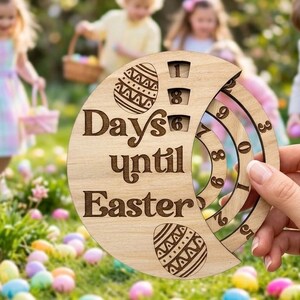 May include: A circular wooden countdown calendar featuring the engraved text Days until Easter, two decorative egg illustrations, and rotating inner rings with numbers to track the remaining days until the holiday, held by a hand.