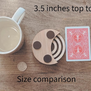 May include: A wooden coaster with three brown circular accents, a playing card, a pencil, a coffee mug, and a coin are arranged on a wooden surface. The text "3.5 inches top to bottom" and "Size comparison" are visible.